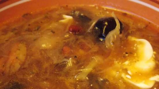 Lean cabbage soup with cabbage, beans, mushrooms and prunes under a bread lid